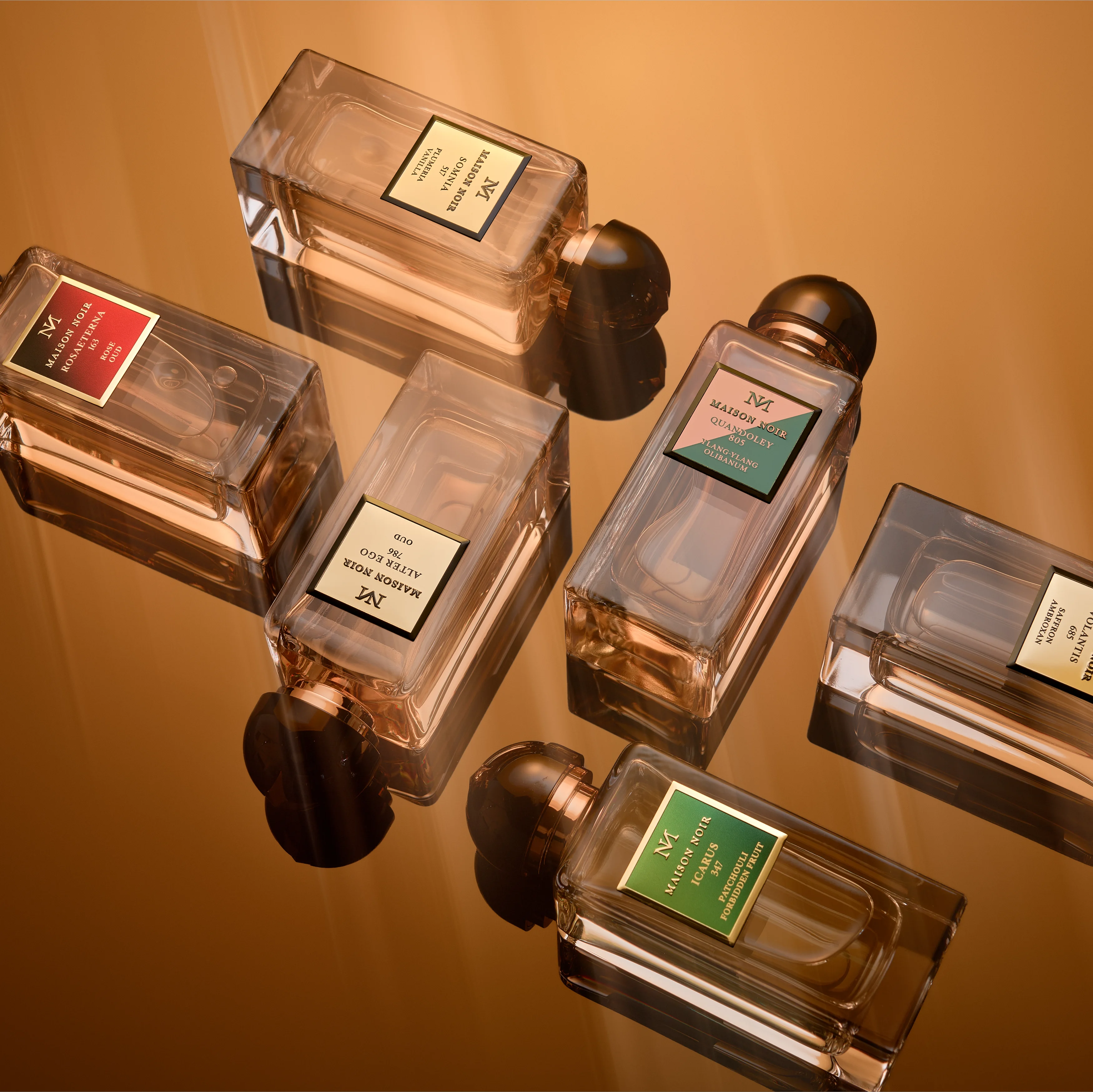 Several Maison Noir flacons suspended together against a warm amber ground