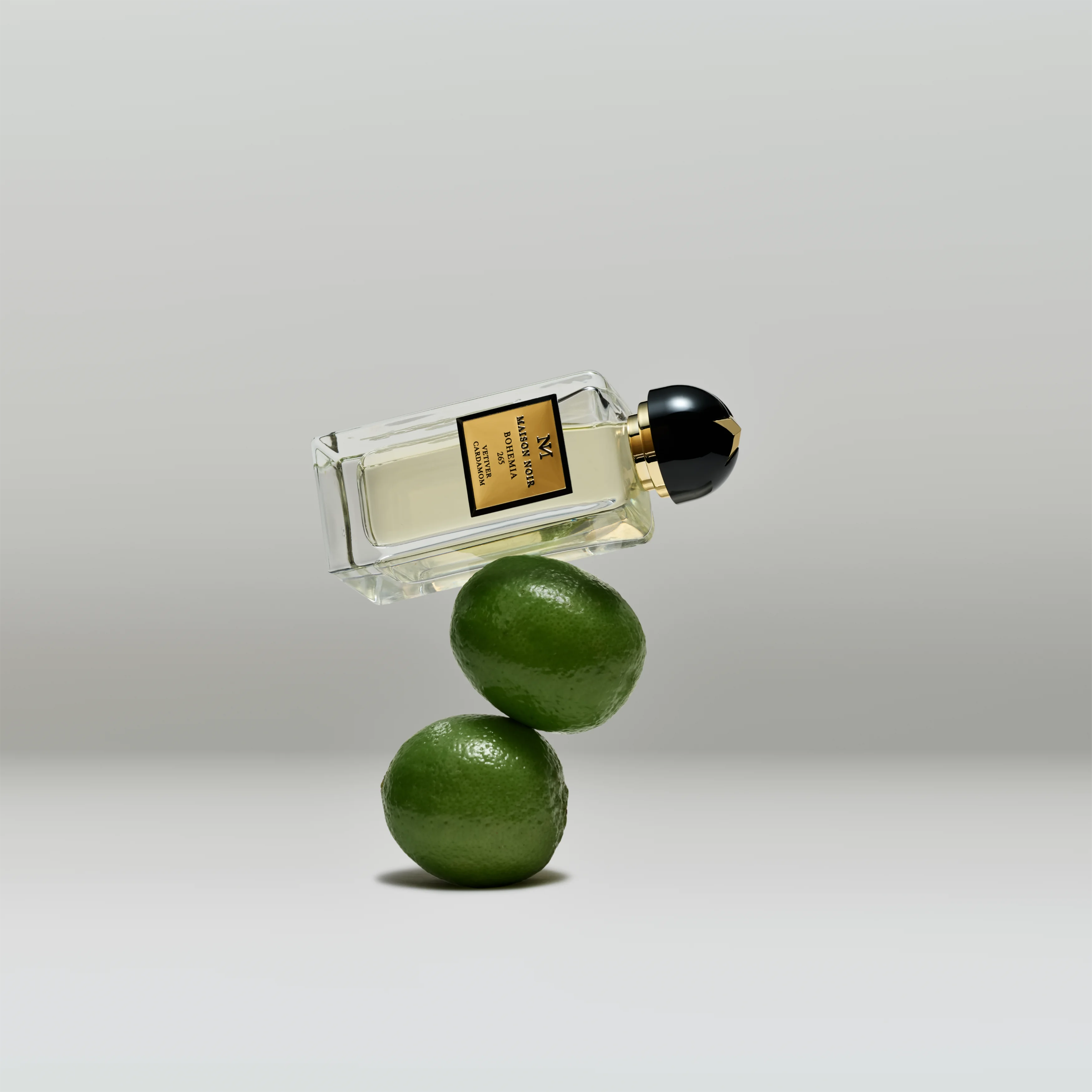 A flacon balanced on two fresh limes against a pale grey ground