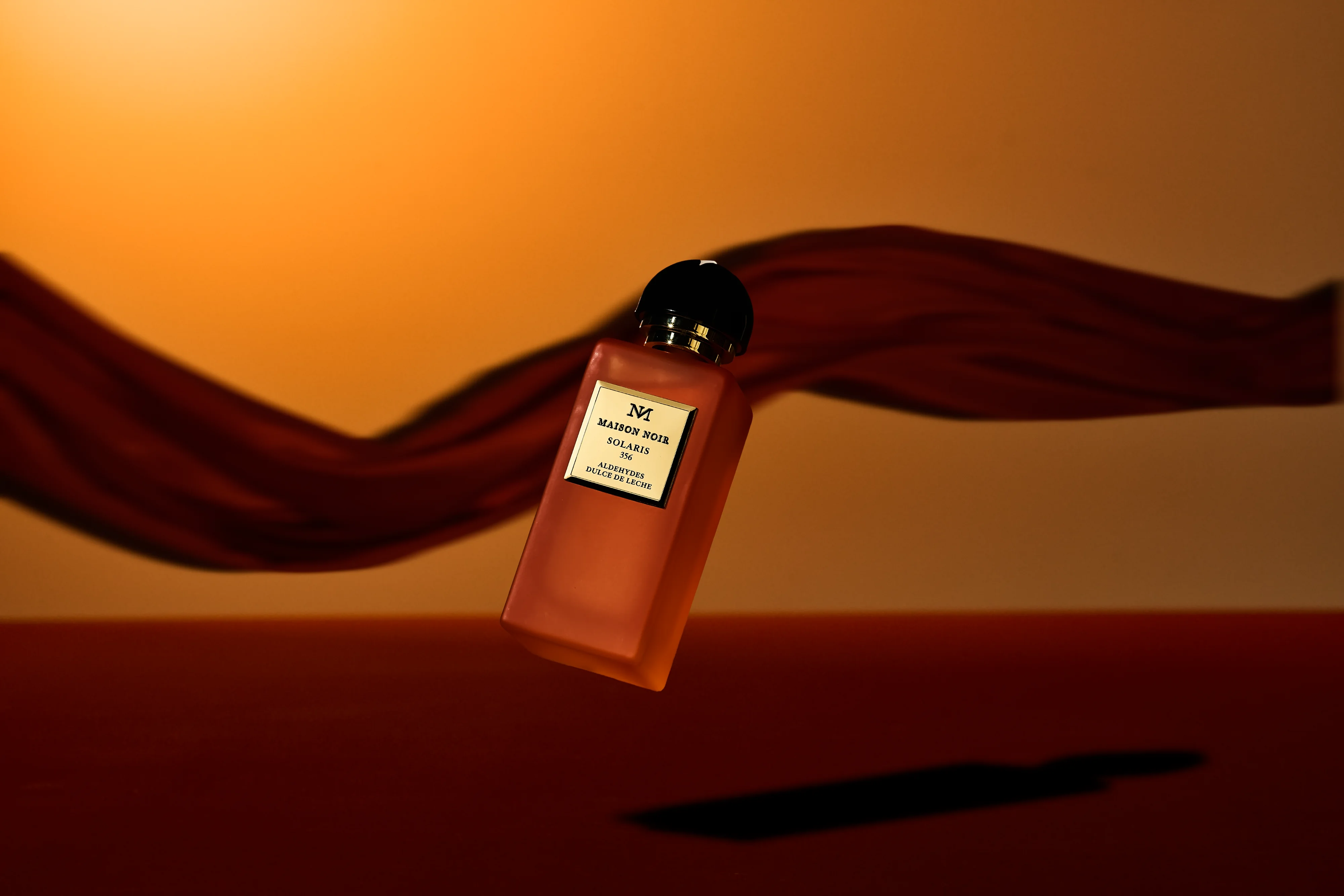 A flacon on a terracotta ground with a length of silk lifting away from it